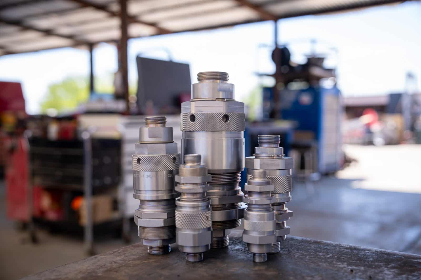 Male and female Flat Face Screw-to-Connect Couplers coupled together on a jobsite. They sit on a table in front of equipment.