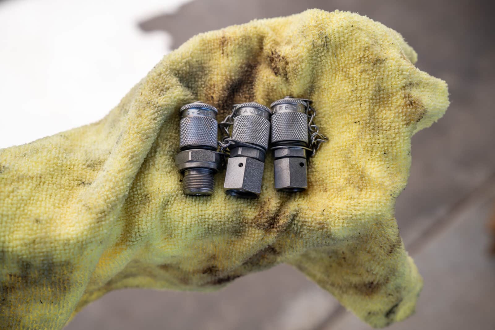 Three Heavy Haul Test couplers behind held by a greasy, used, yellow work towel